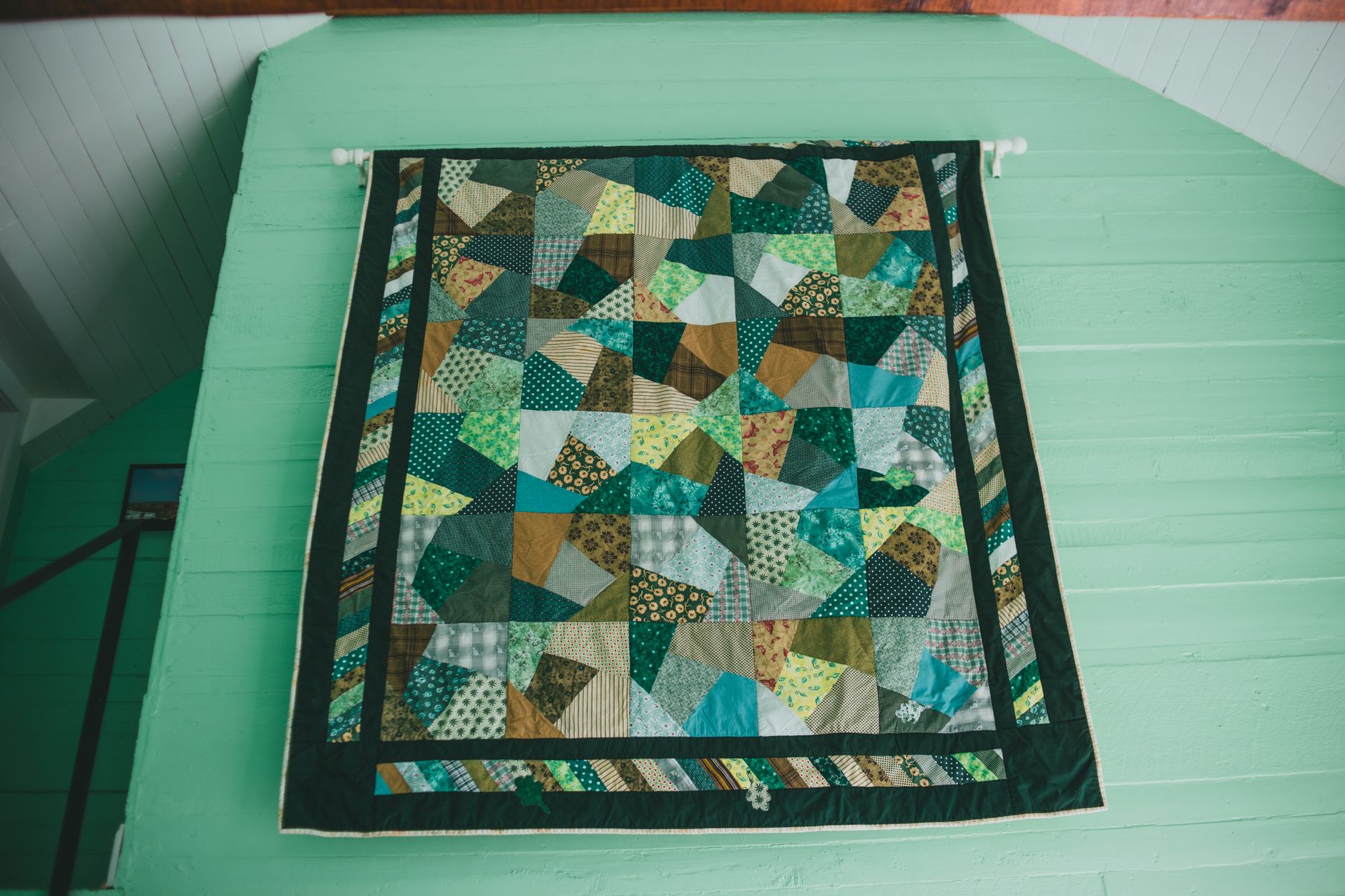 A patchwork quilt on a green wall