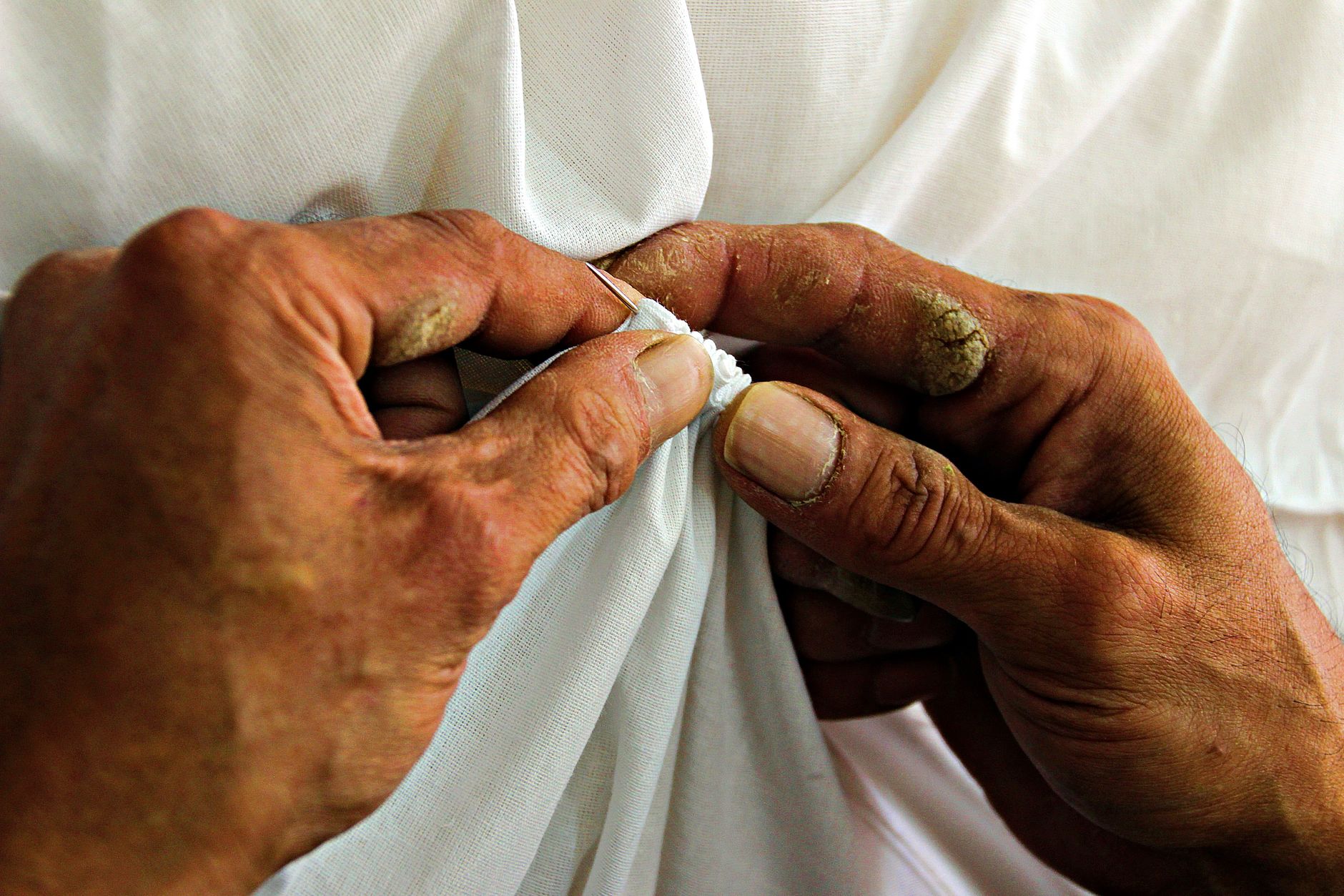 Hands stitching white fabric