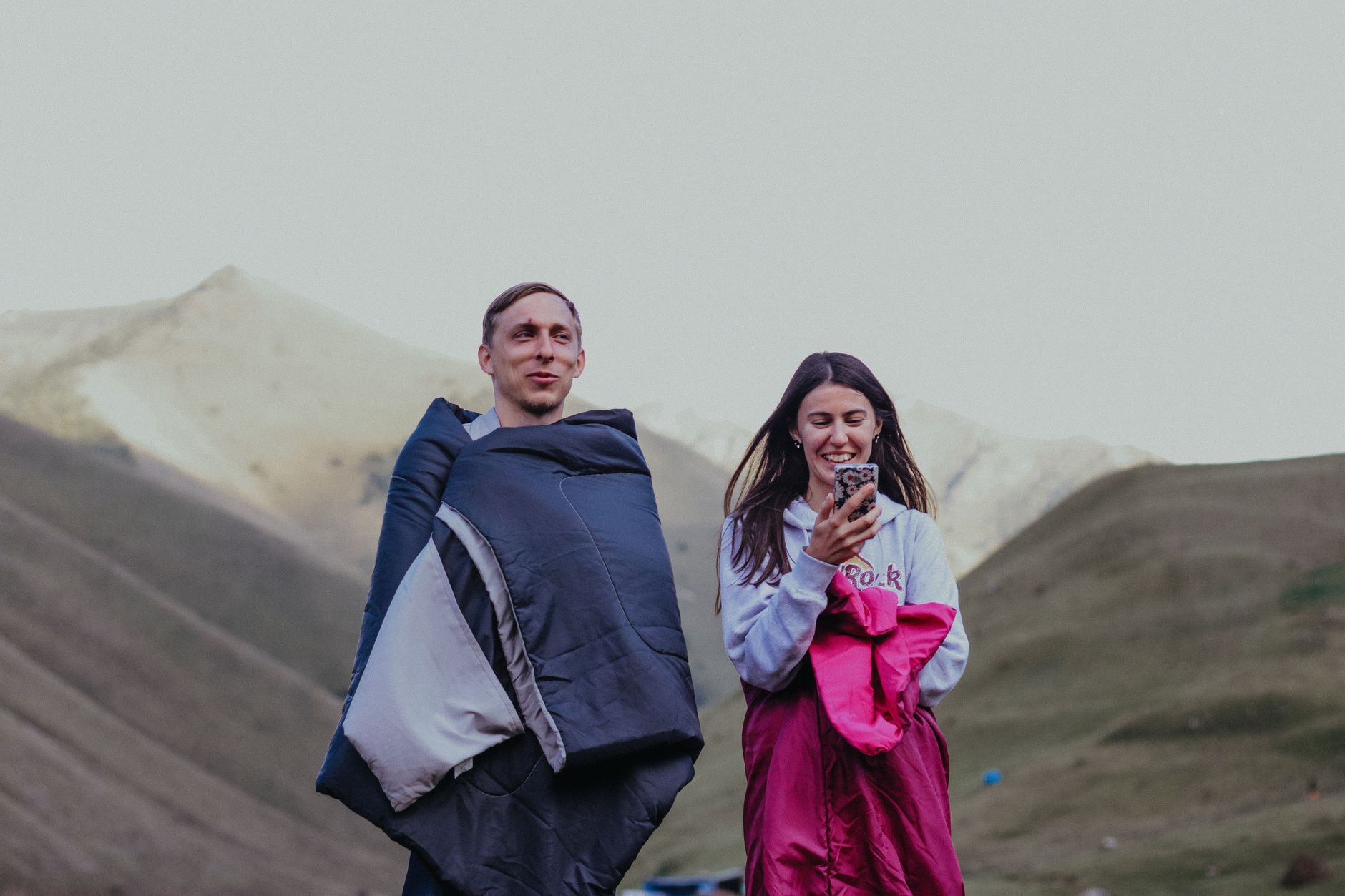 Two people wrapped in sleeping bags outdoors