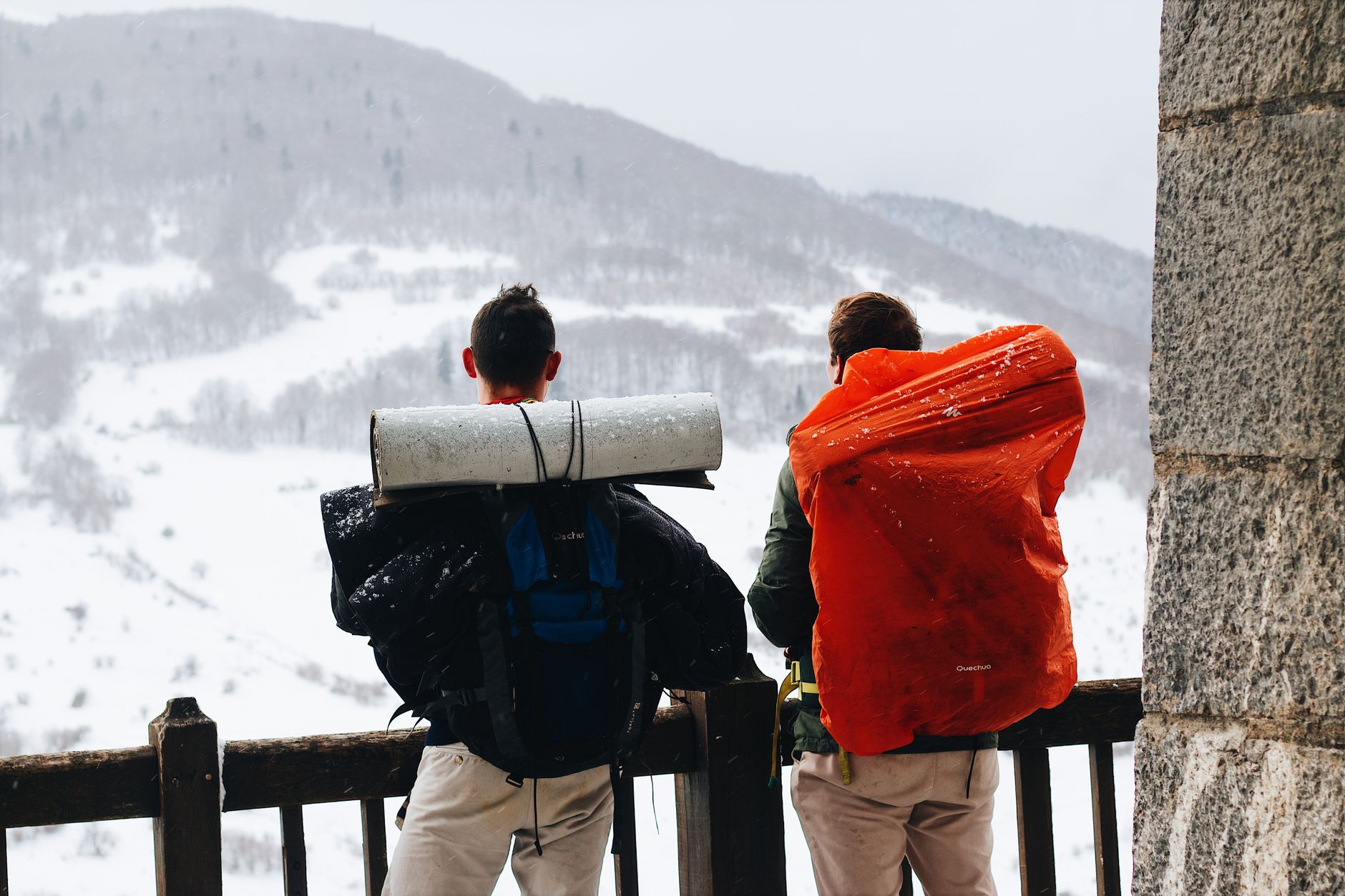 Two backpackers looking at snowy mountains