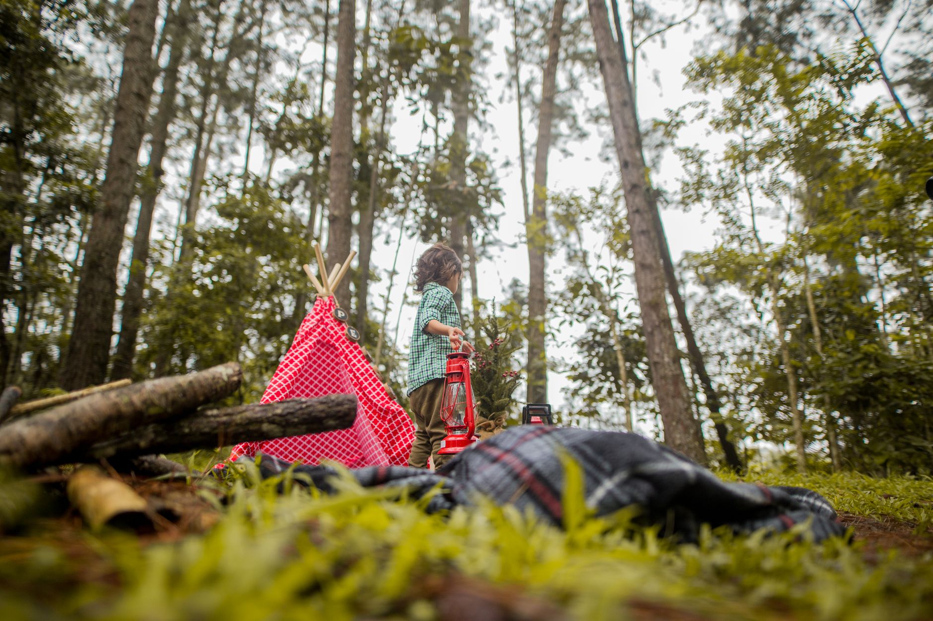 A child near a tent and sleeping bag in the woods