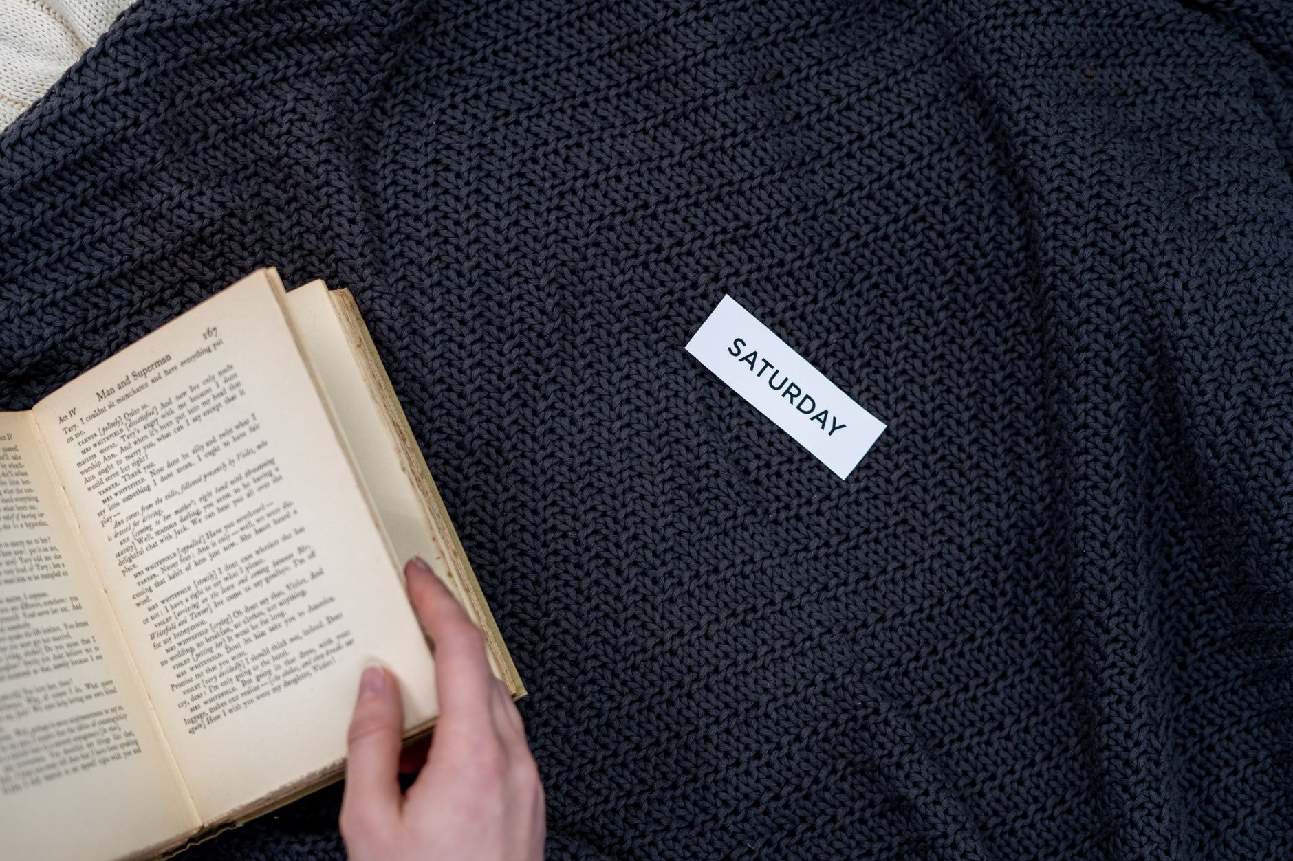 A person reading under a dark knit blanket