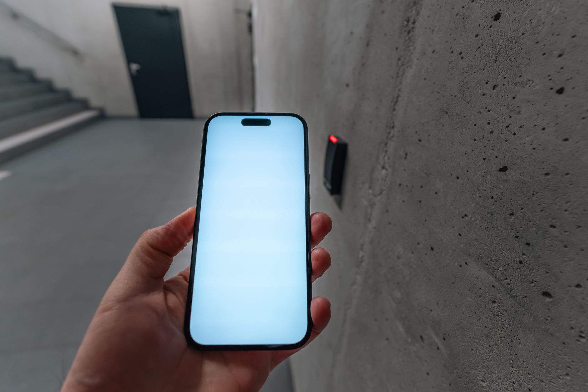 A hand holding a smartphone in a concrete stairwell