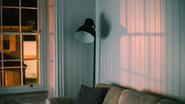A floor lamp and sofa by a window at dusk