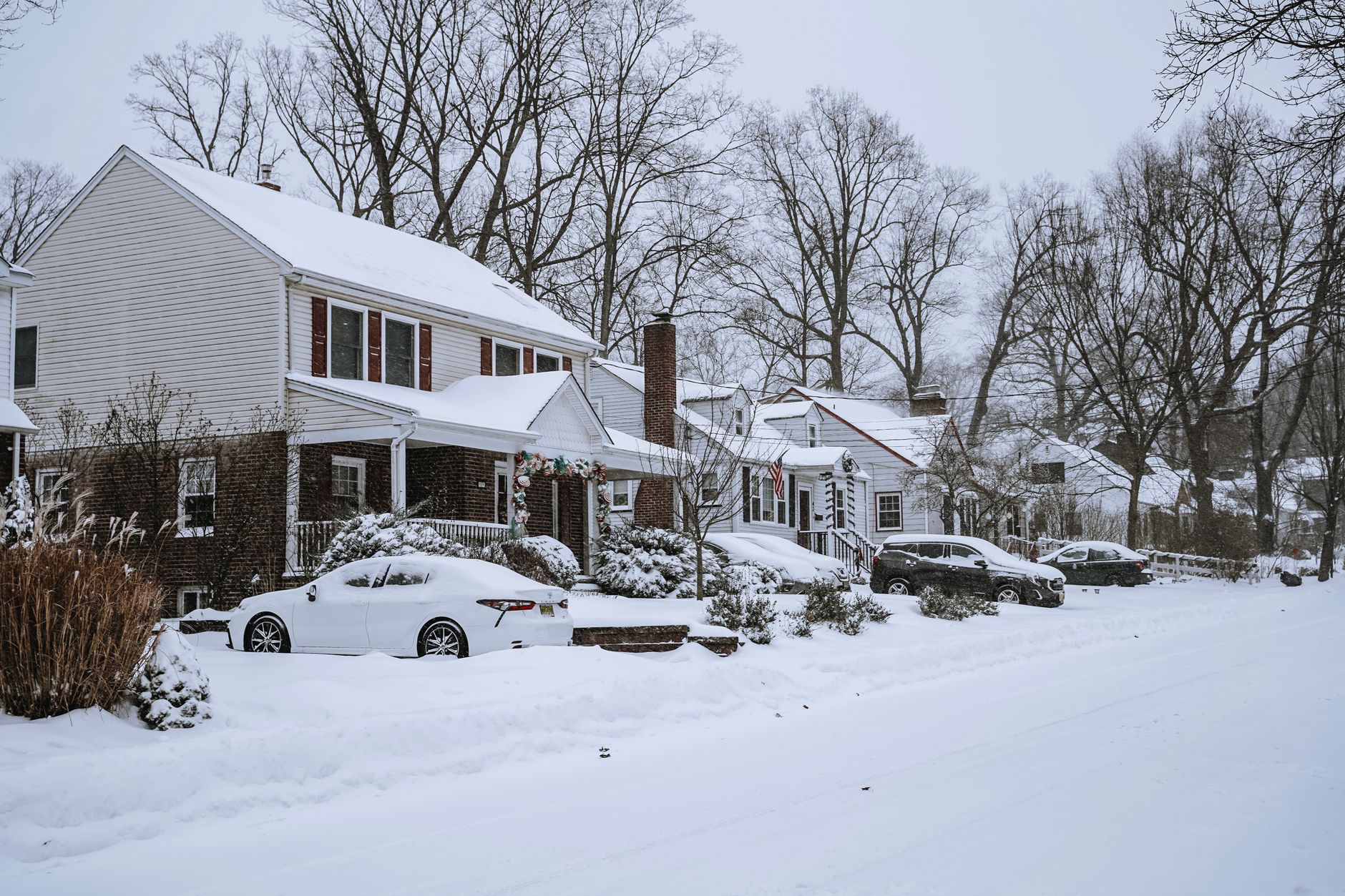 Snow-covered houses and cars on a residential street