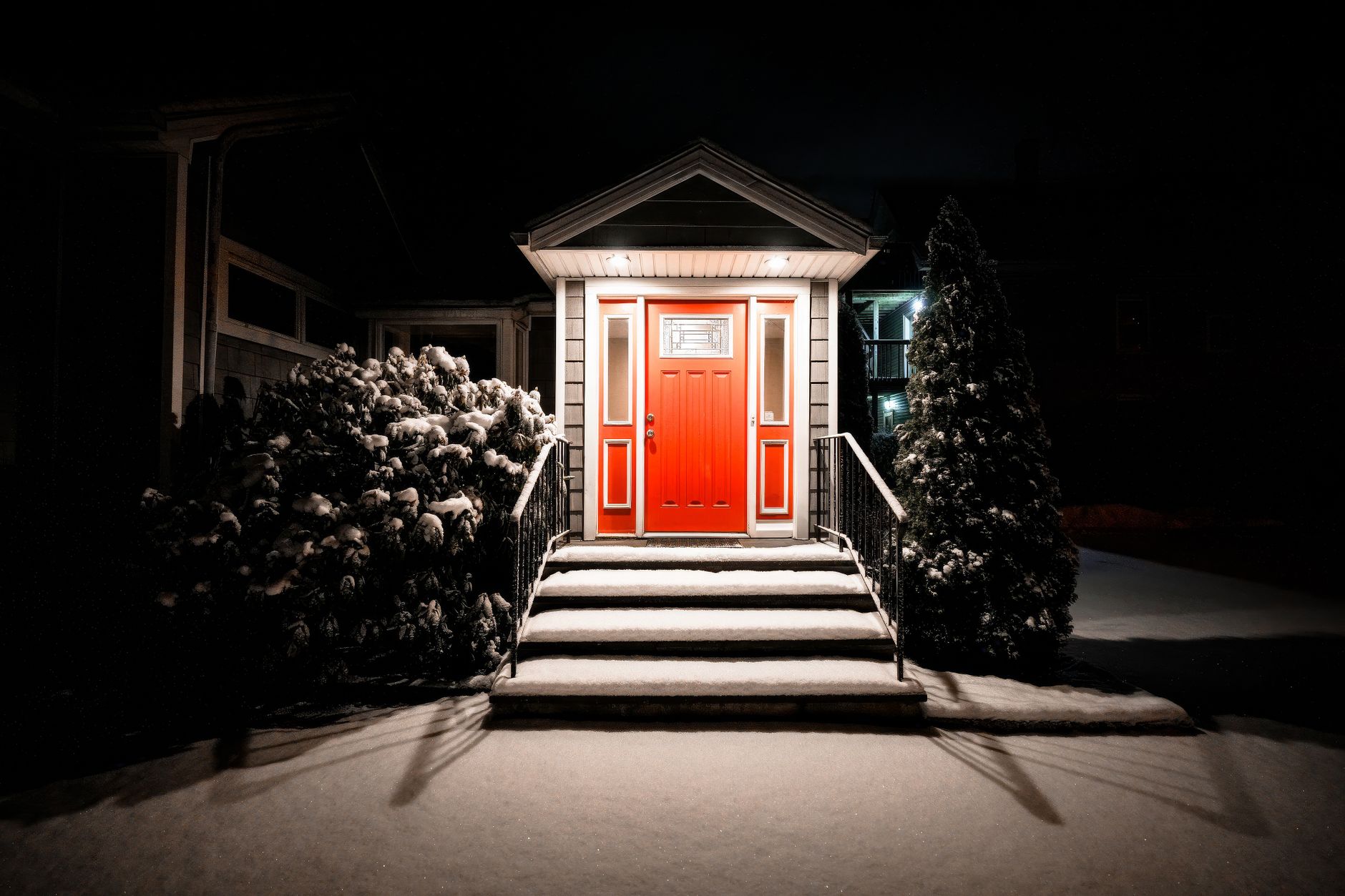 Lit front steps leading to a red door at night