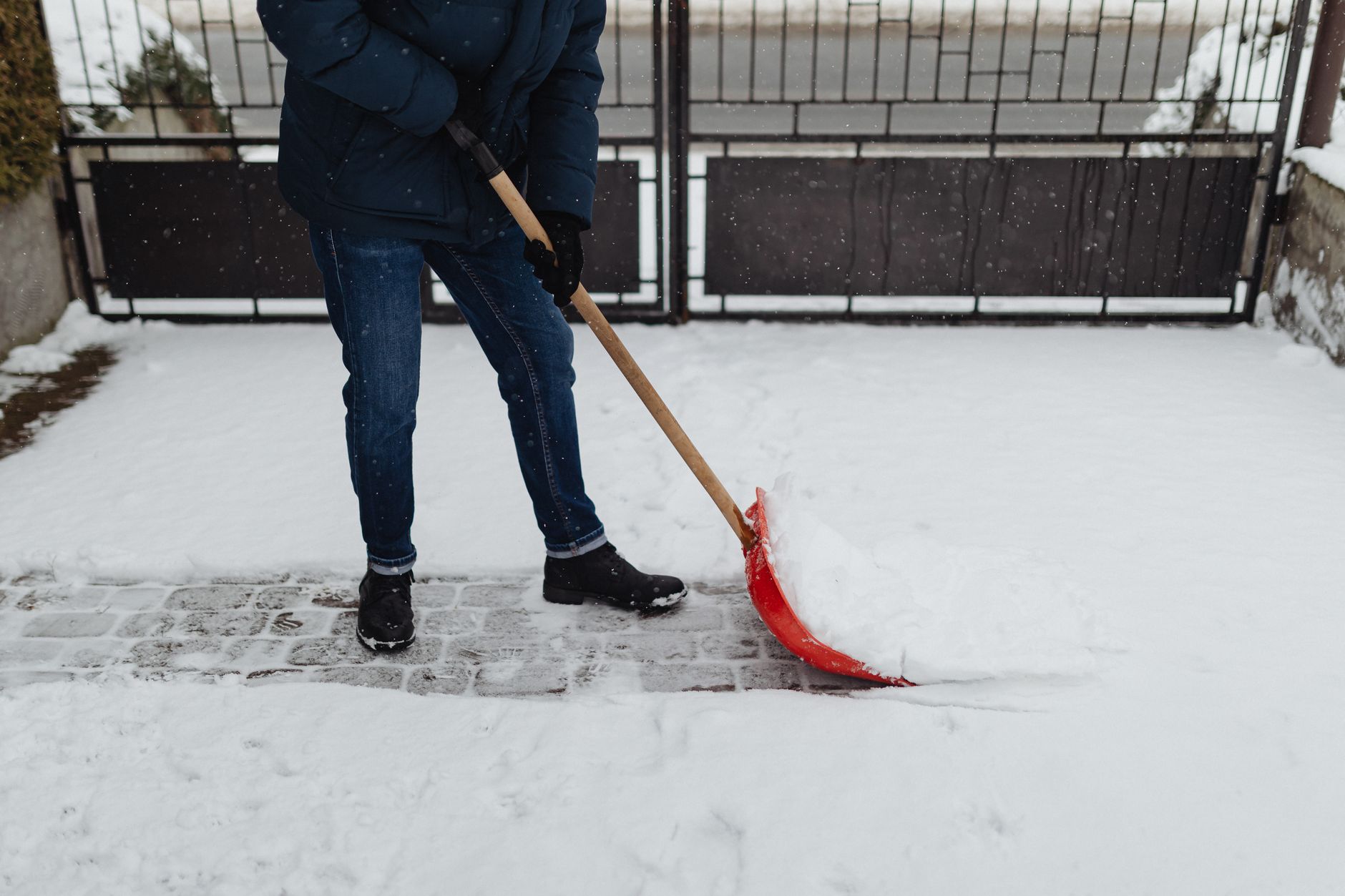 A person shoveling snow off a paved driveway