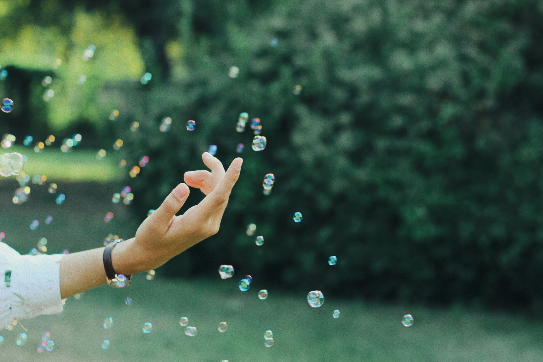 A hand reaching toward floating bubbles