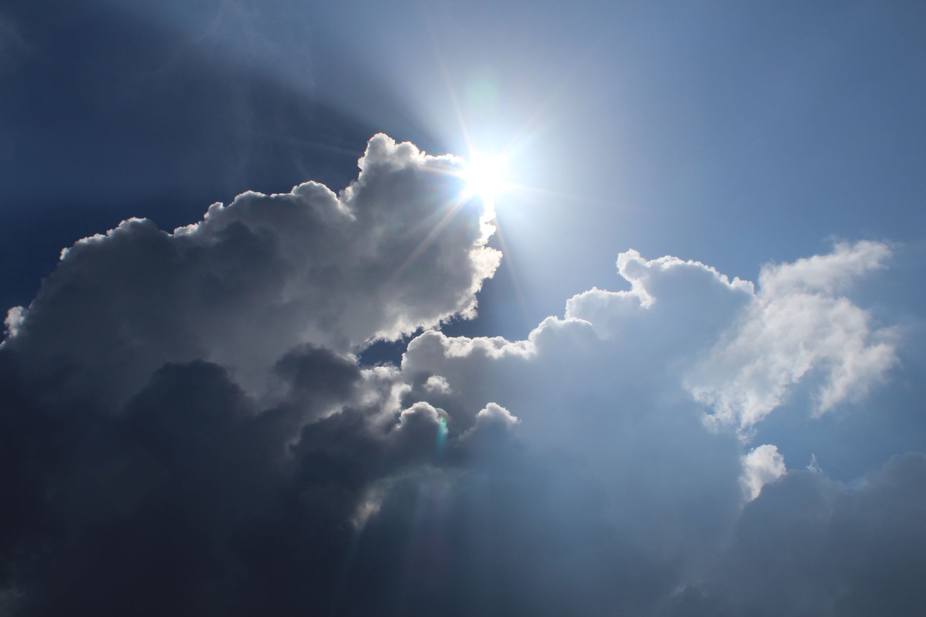 The sun behind clouds in a blue sky