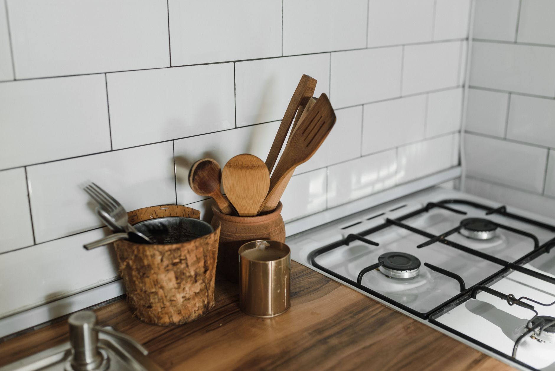 Wooden utensils in a crock beside a gas stove