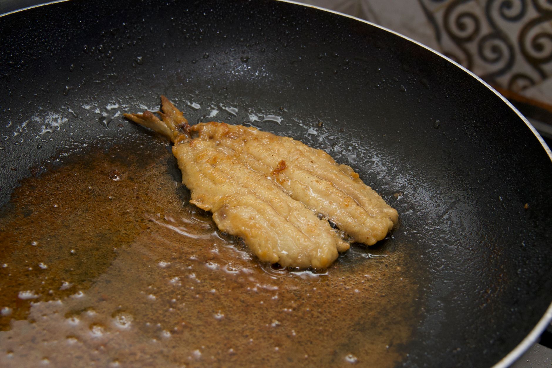 A fish fillet frying in a pan