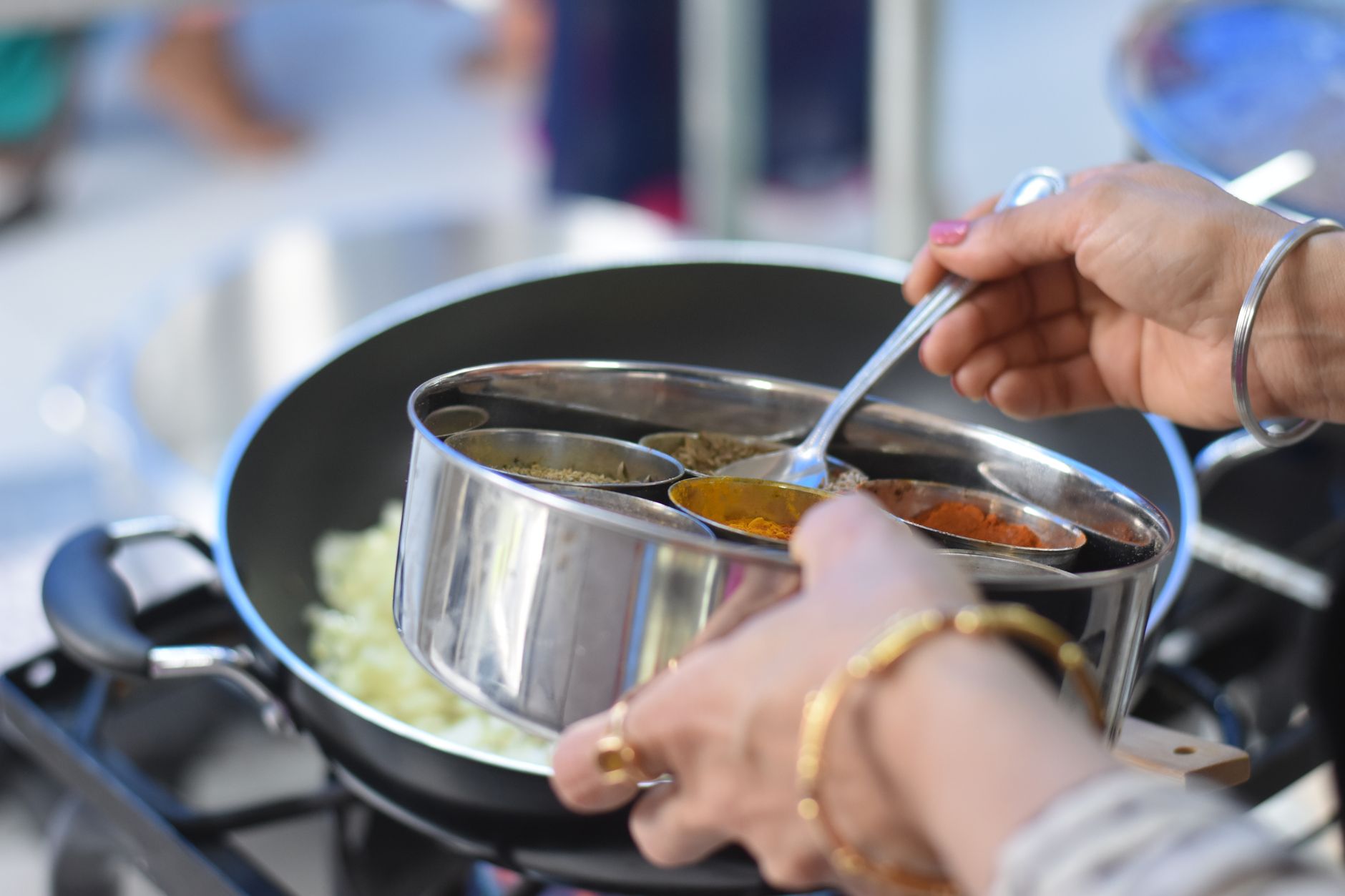 Spices being added to food in a pan