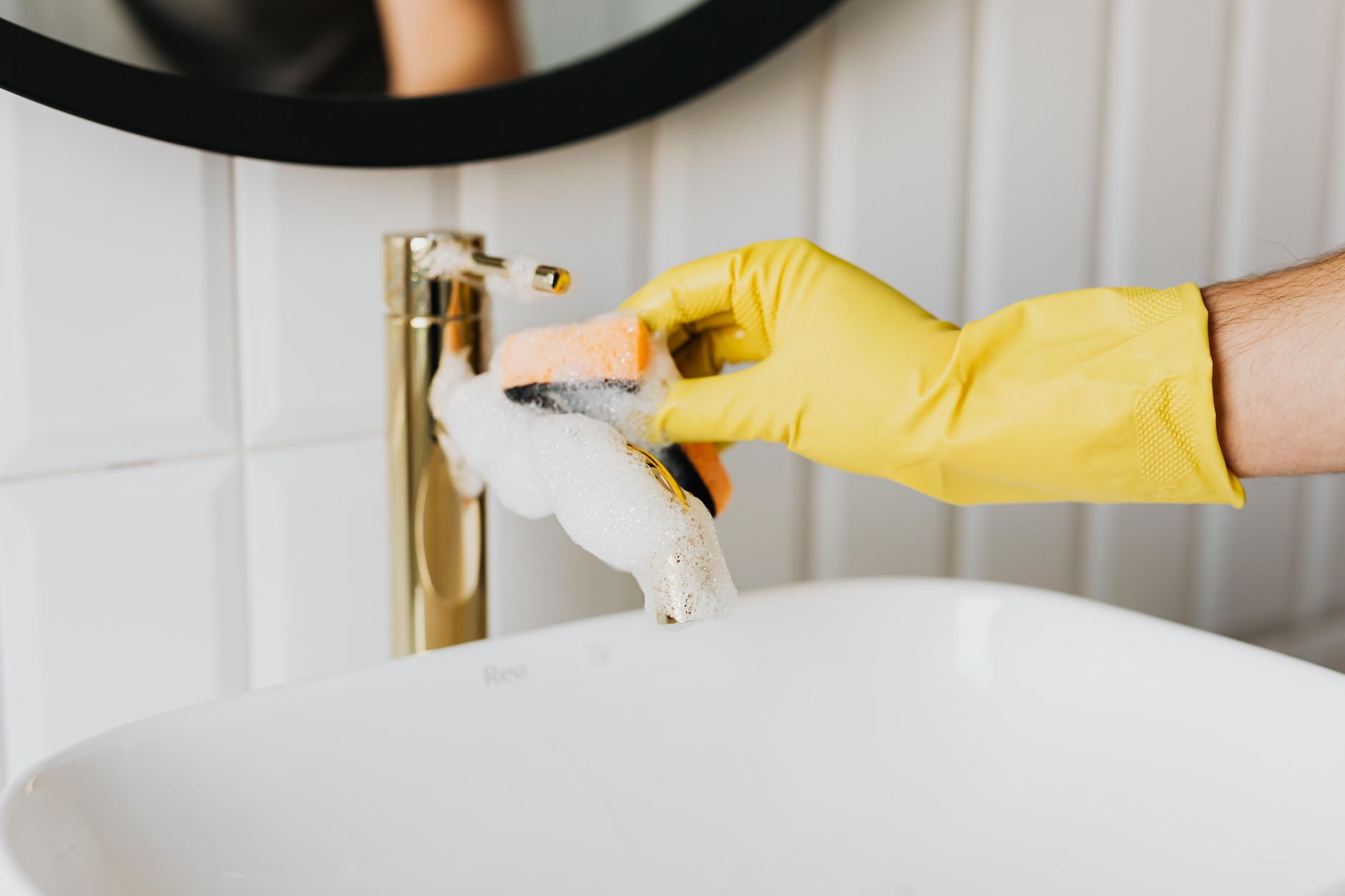 Scrubbing a faucet with a gloved hand