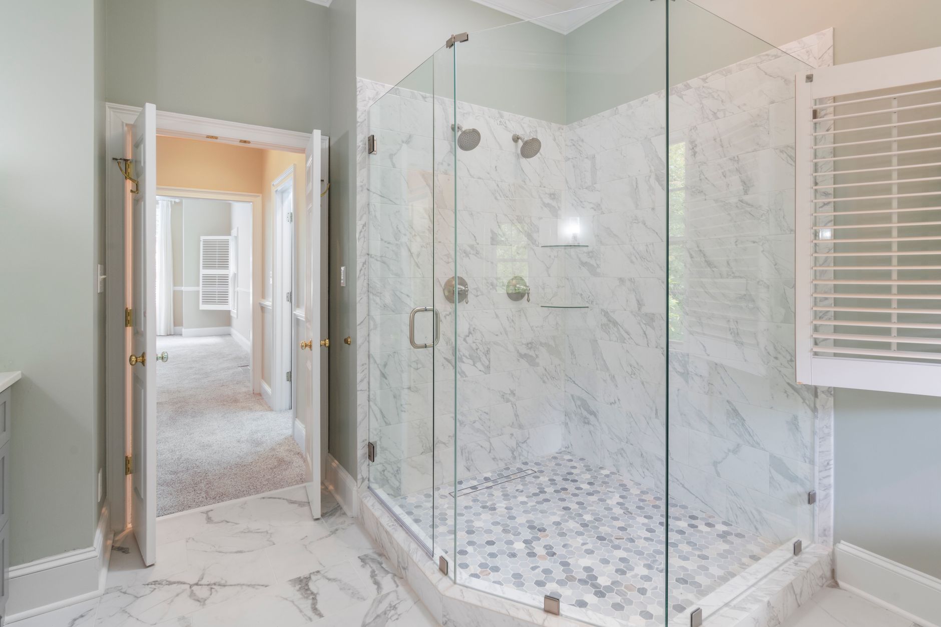 A glass shower enclosure with marble tile