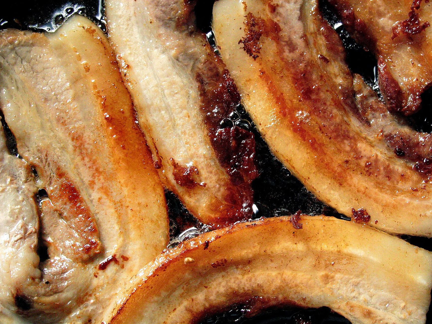 Best splatter screen: pork slices frying in a pan