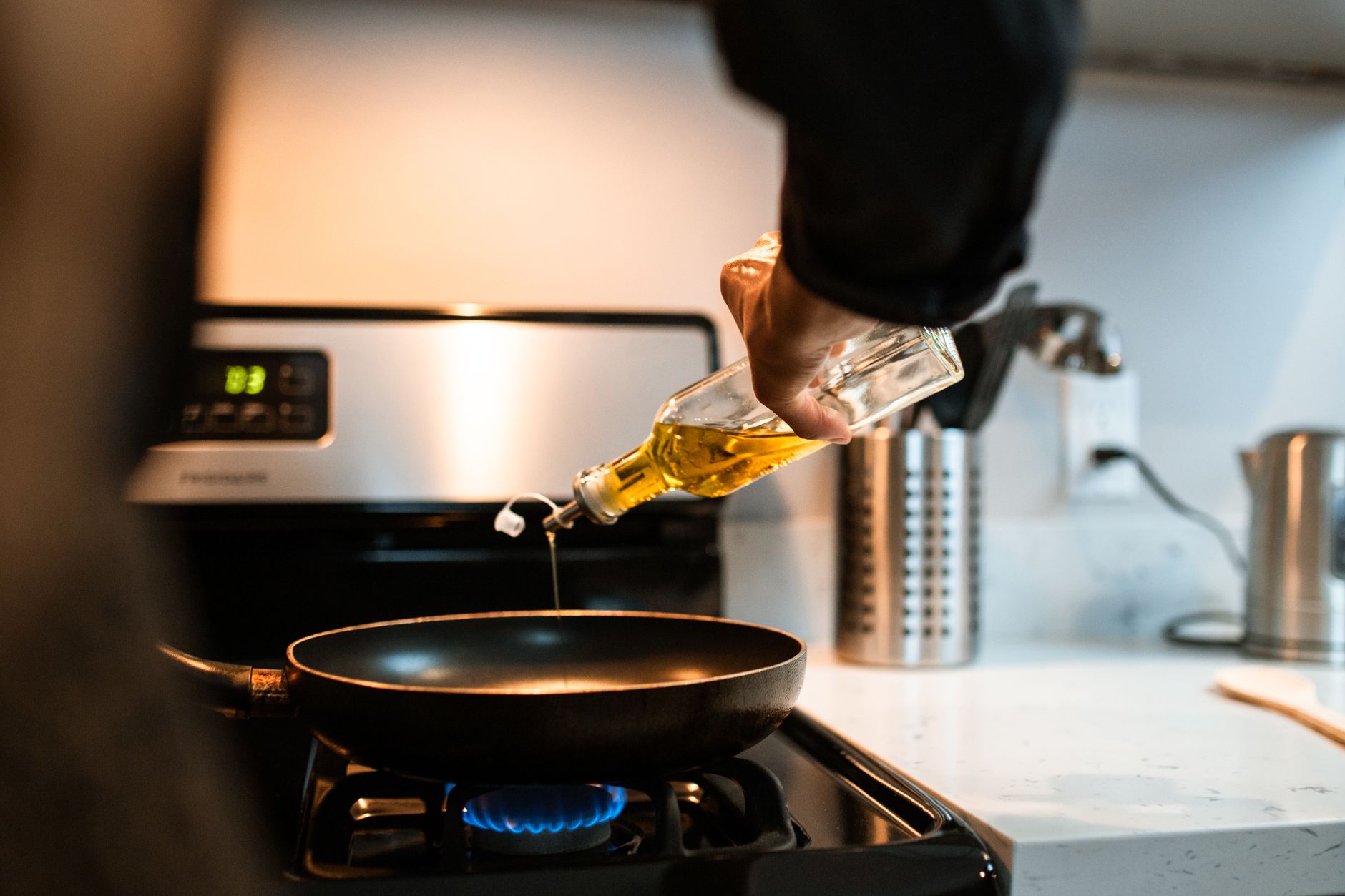 Pouring oil into a frying pan on a gas stove