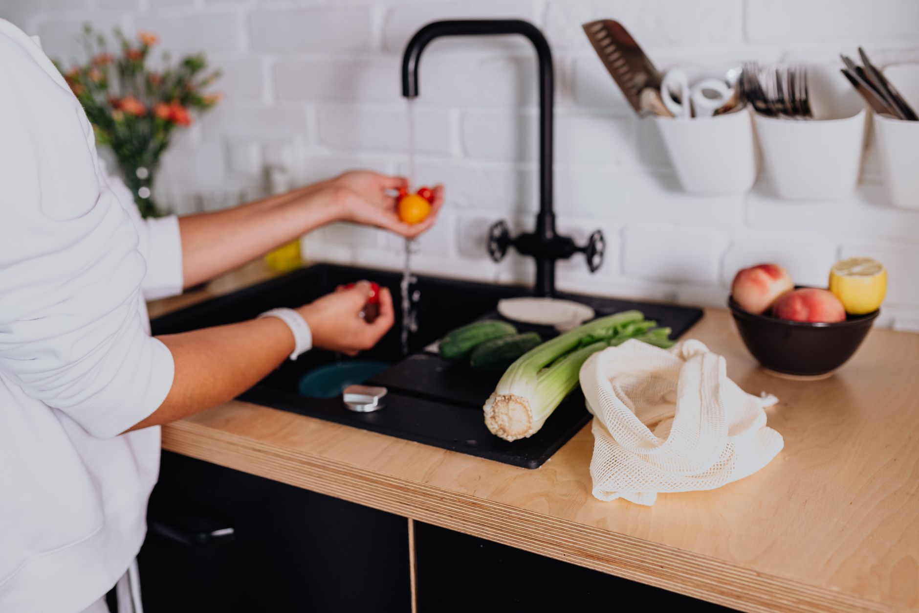Hands washing dishes at a kitchen sink