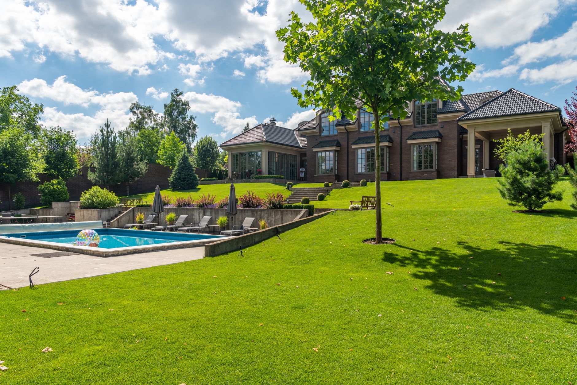 A large lawn with a pool and trees
