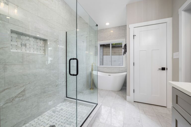 A glass shower beside a freestanding tub