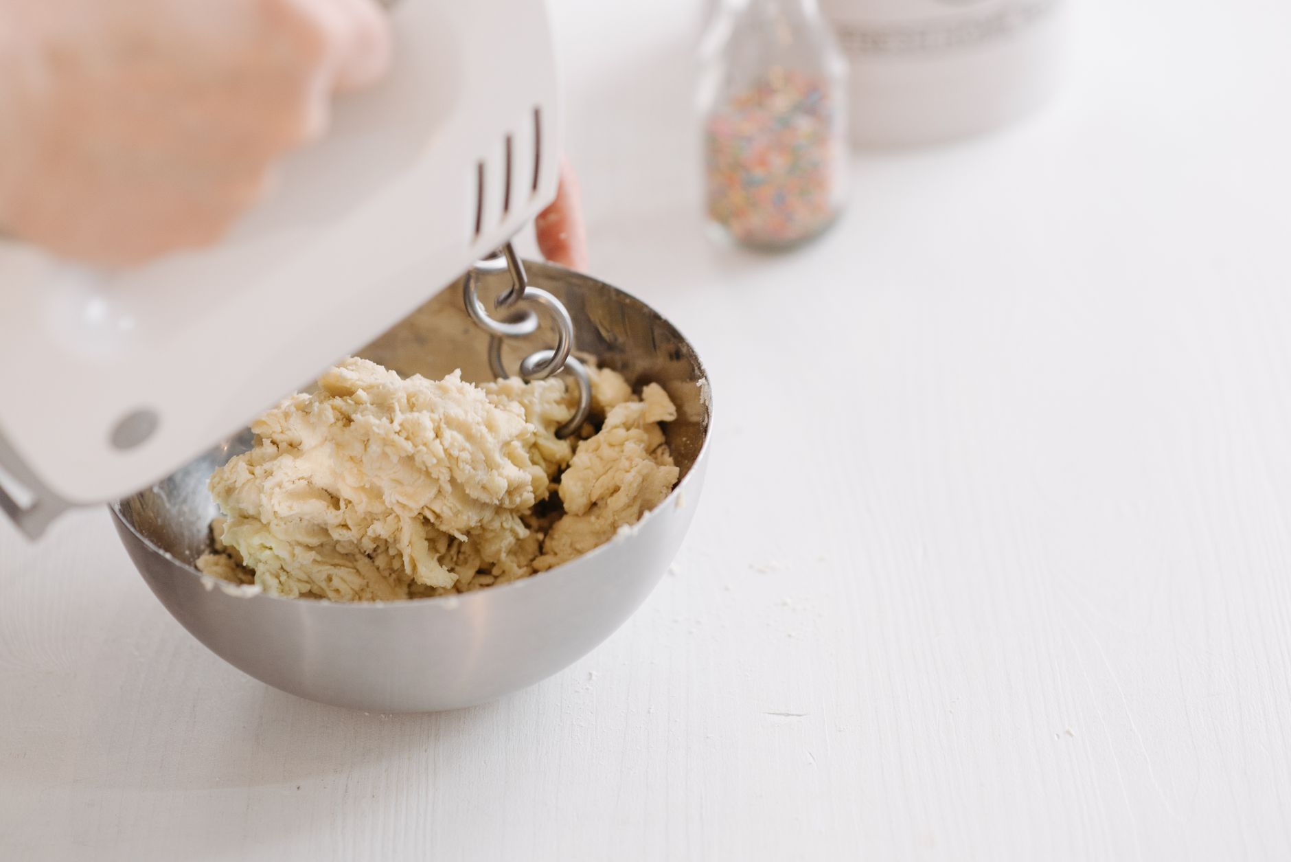 A hand mixer beating dough