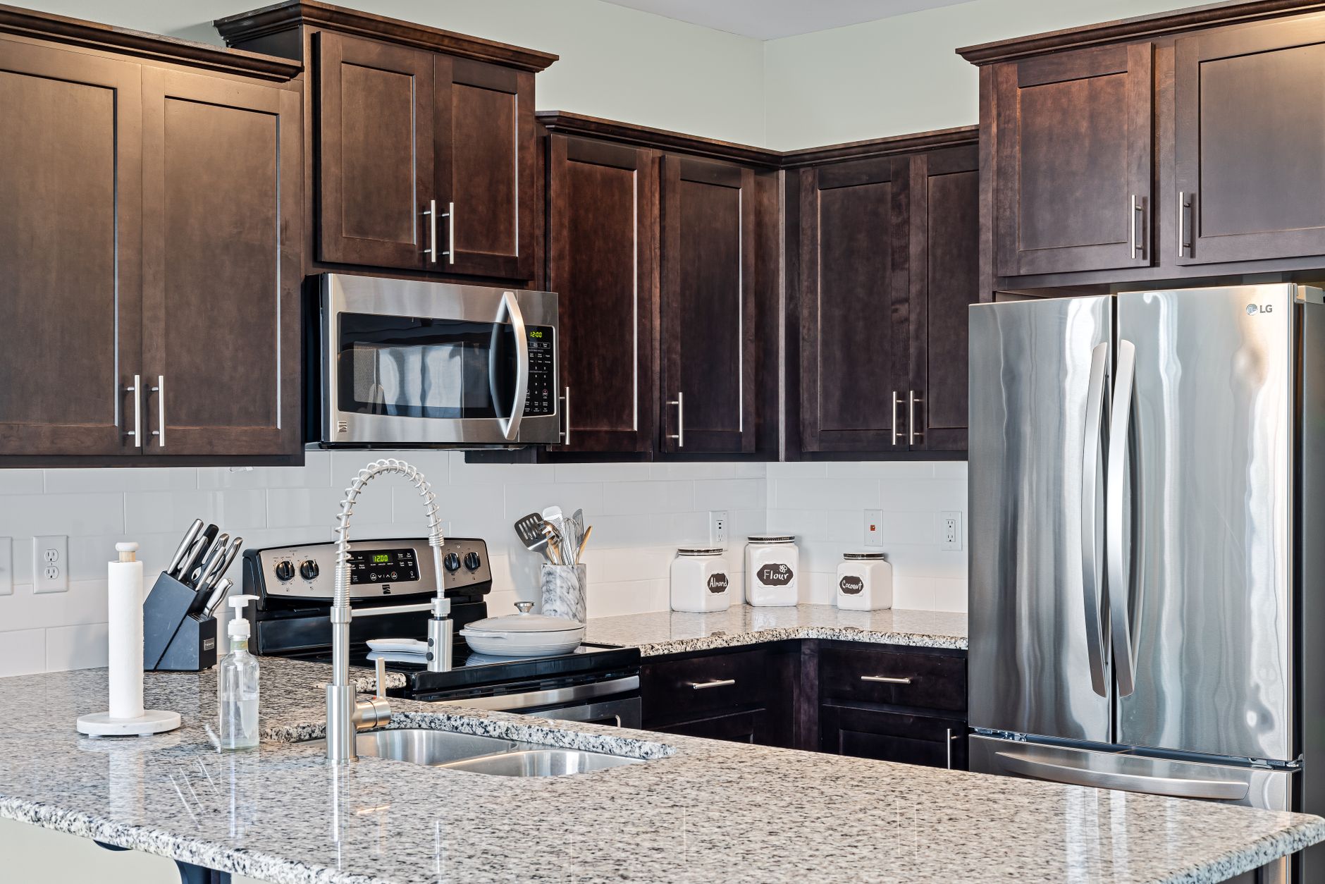A kitchen with dark cabinets and stainless appliances