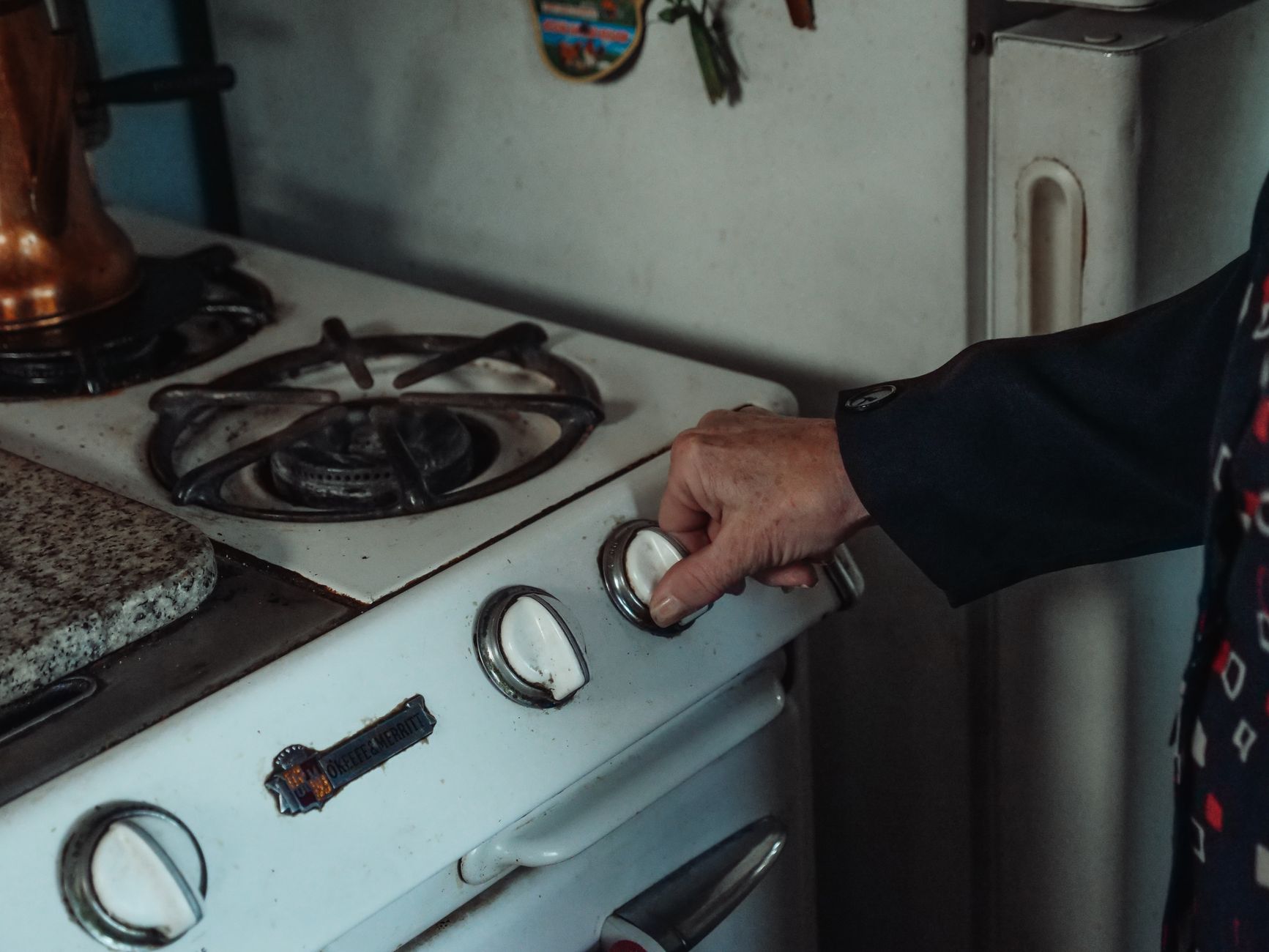 A hand turning a control knob on a gas range