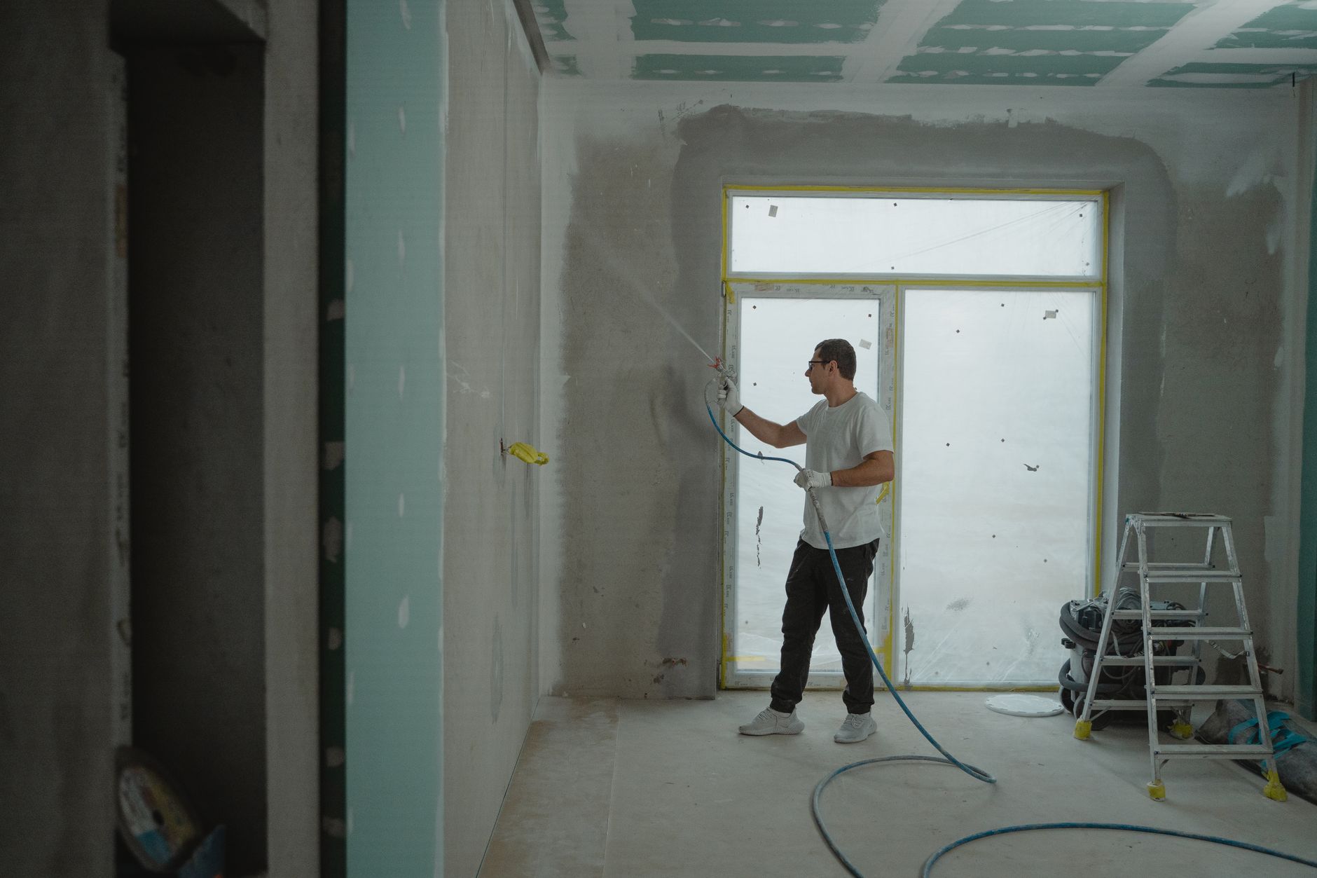 A worker spraying a wall in a gutted room