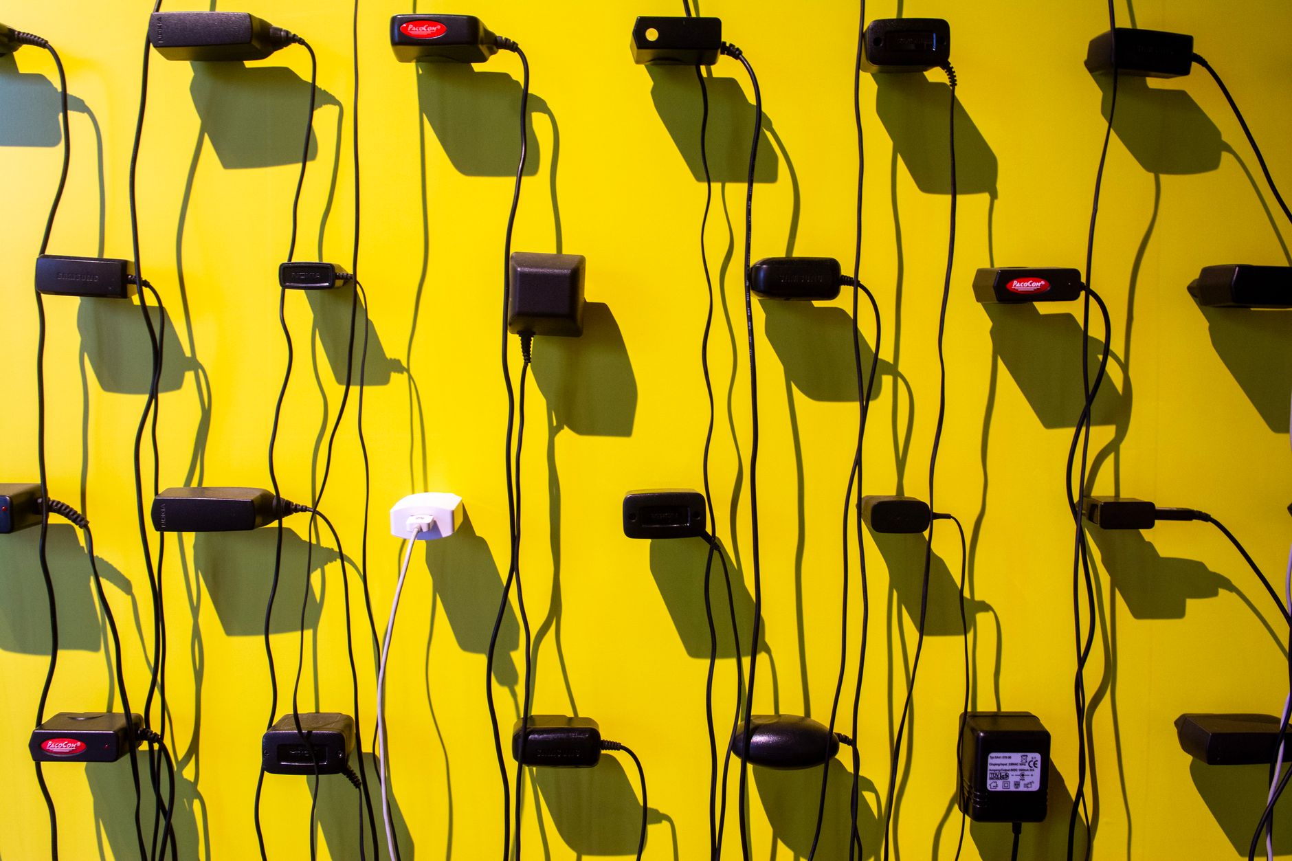 Chargers and cords hung on a yellow wall