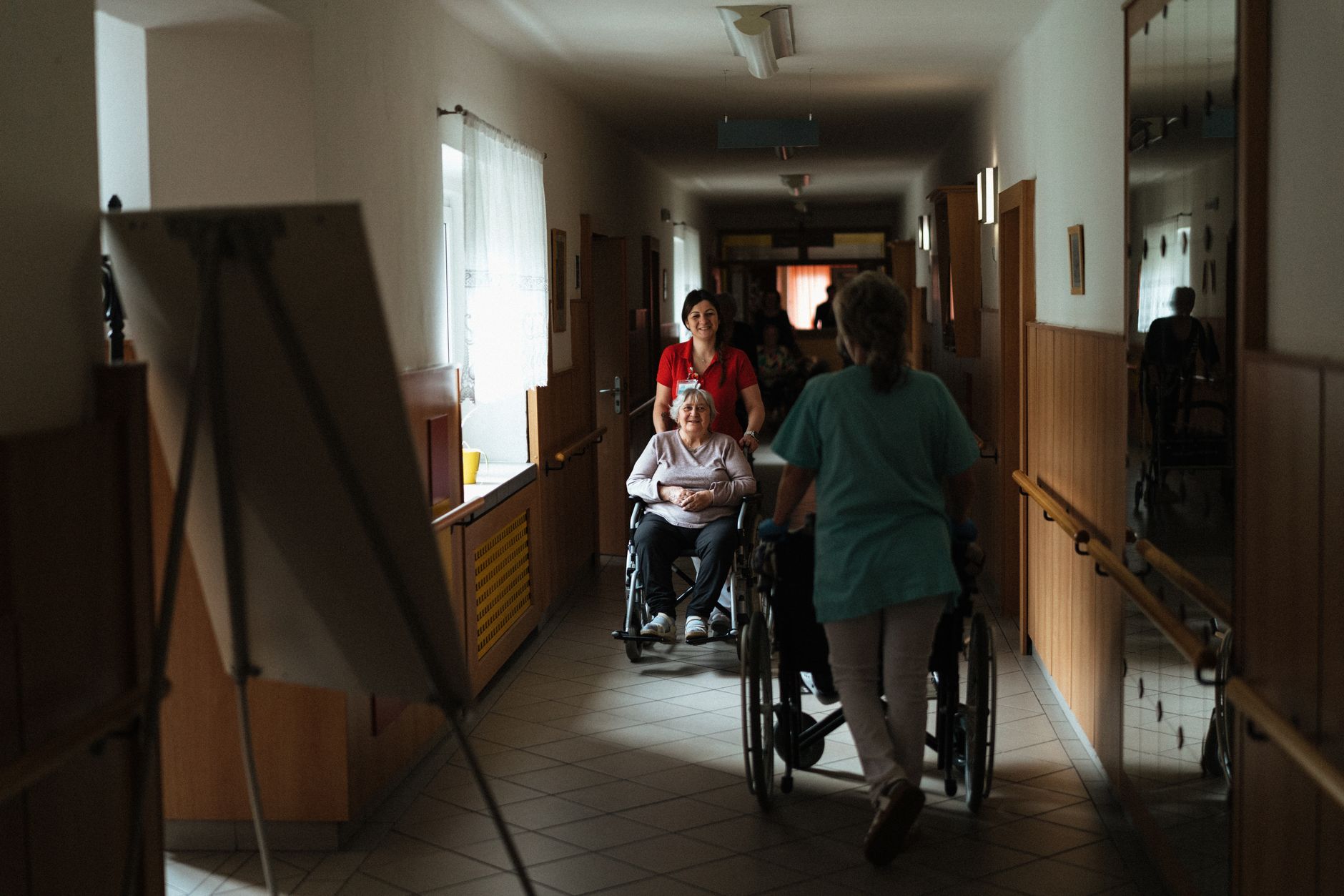 Caregivers pushing wheelchairs down a hallway