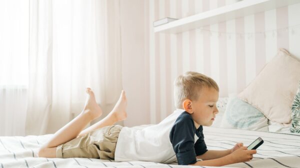 A young boy lying on a bed with a tablet