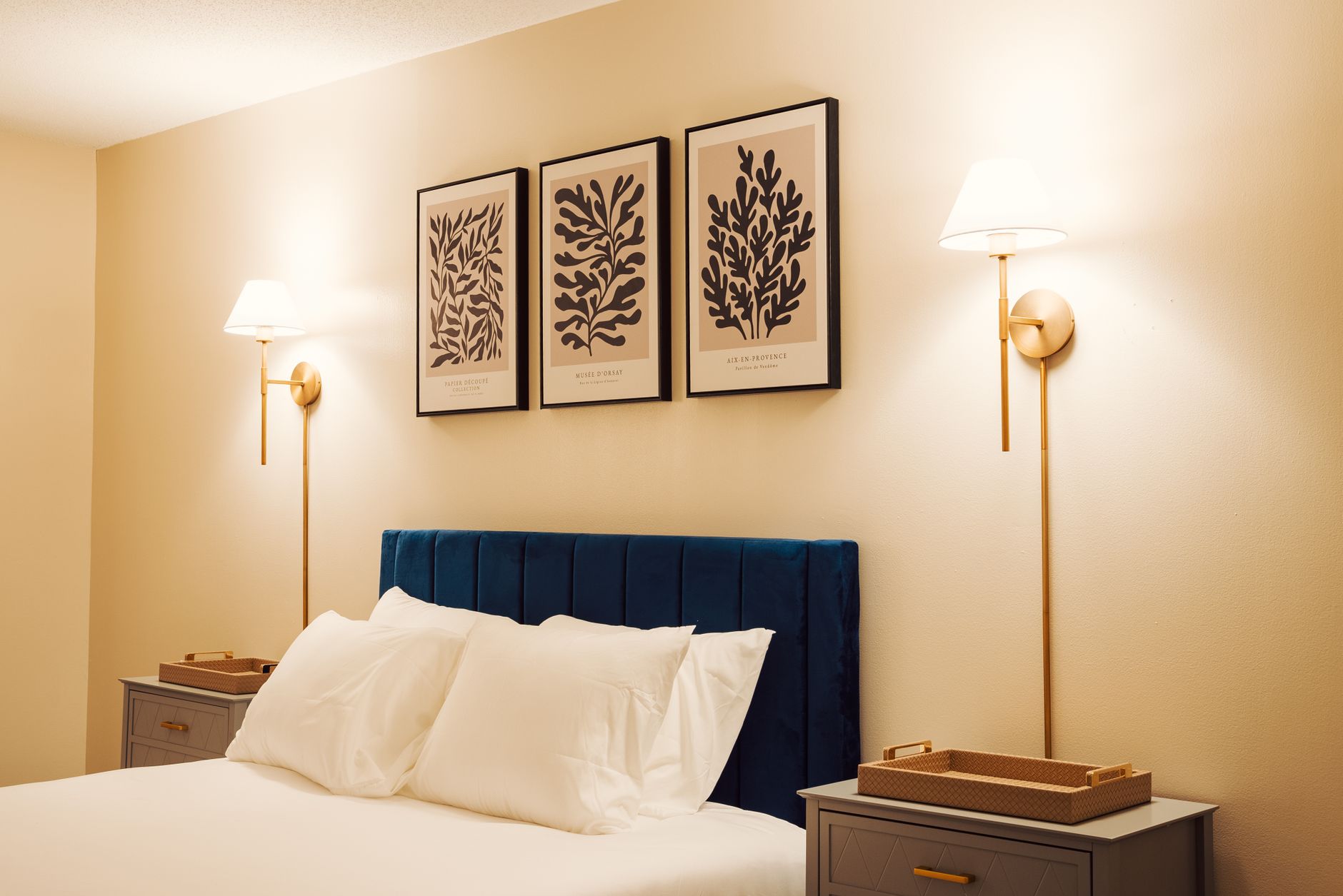 A bed with a blue headboard and wall lamps
