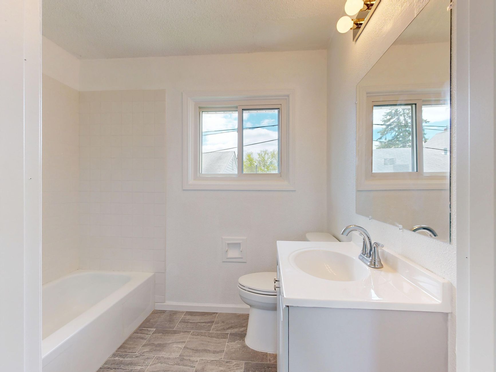 A bright bathroom with a tub and toilet