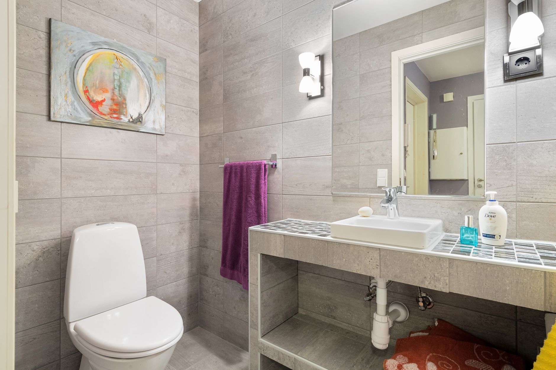 A tiled bathroom with a toilet and vanity