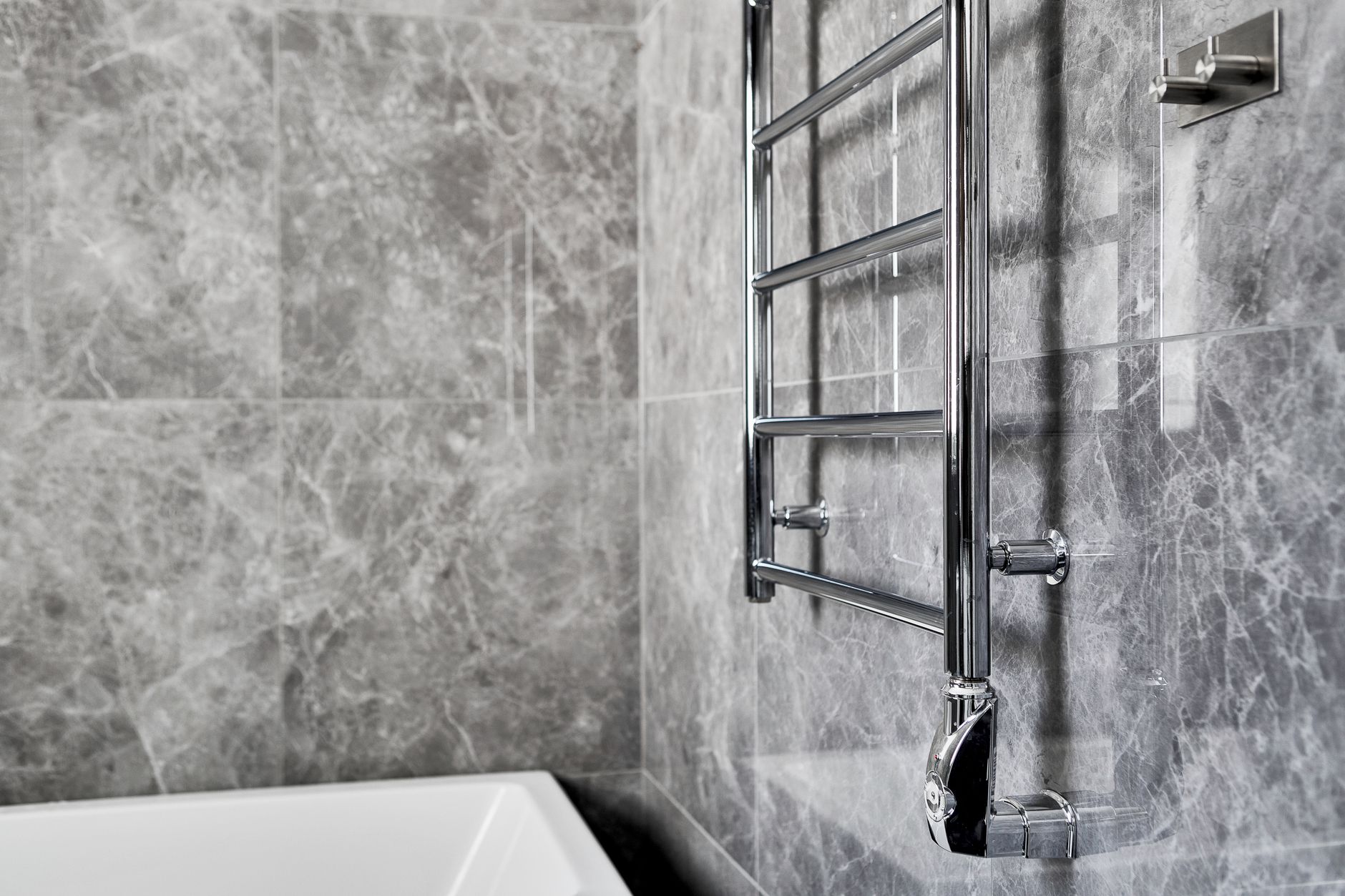 A heated towel rail on a marble wall