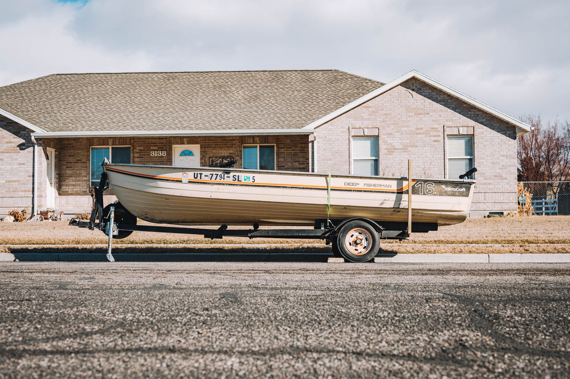 A boat on a trailer parked outside a house