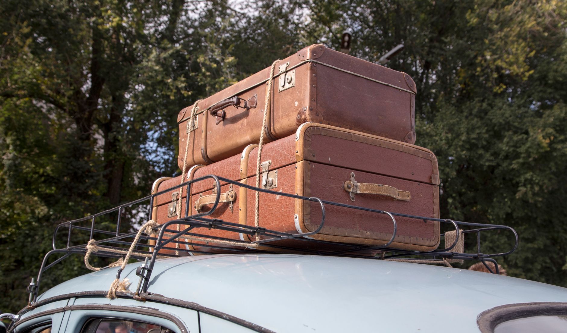 Suitcases strapped to a car roof rack