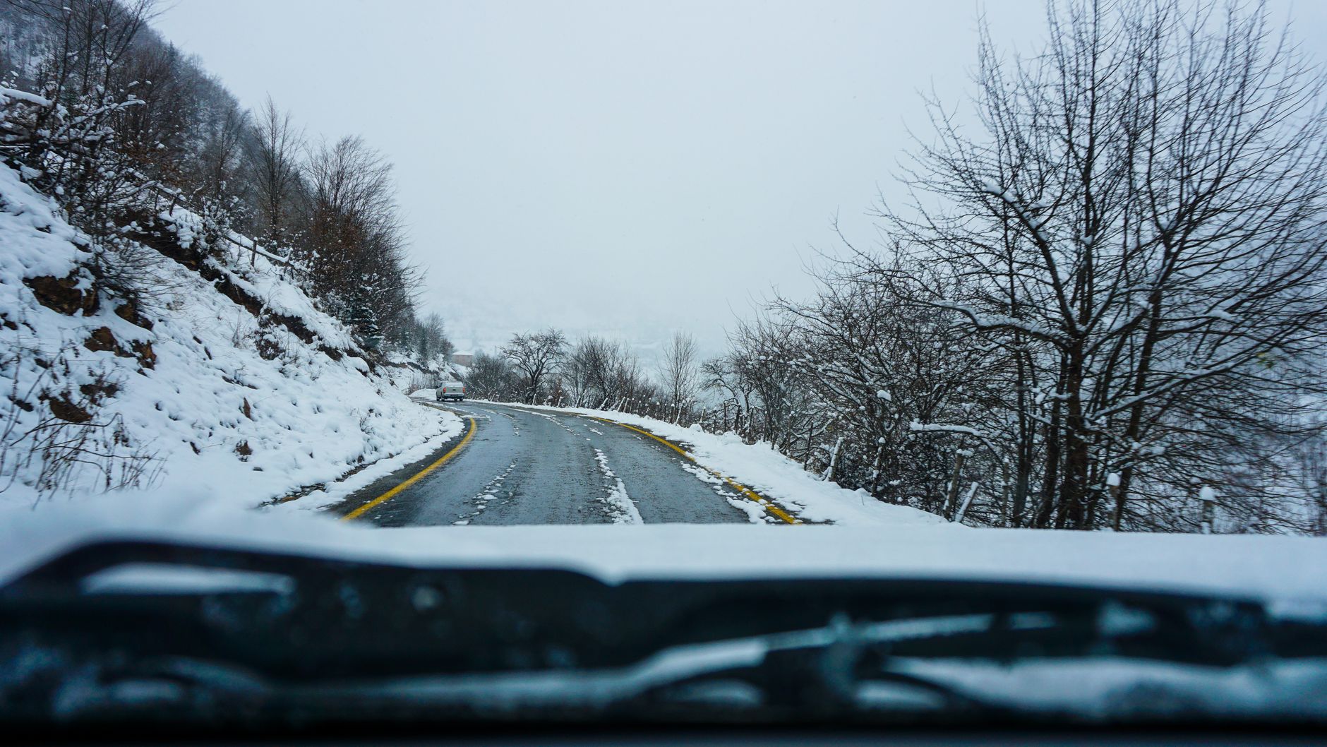 A snowy road seen through a windshield