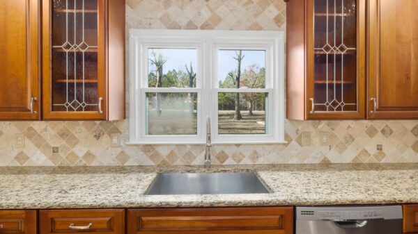 Best under sink organizer: a kitchen sink under a window with wood cabinets