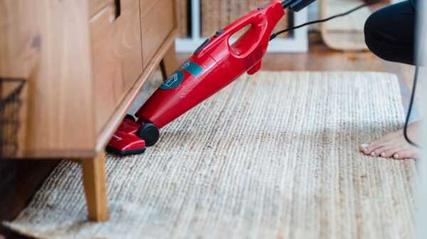 Best upright vacuum: vacuuming a jute rug with a red stick vacuum