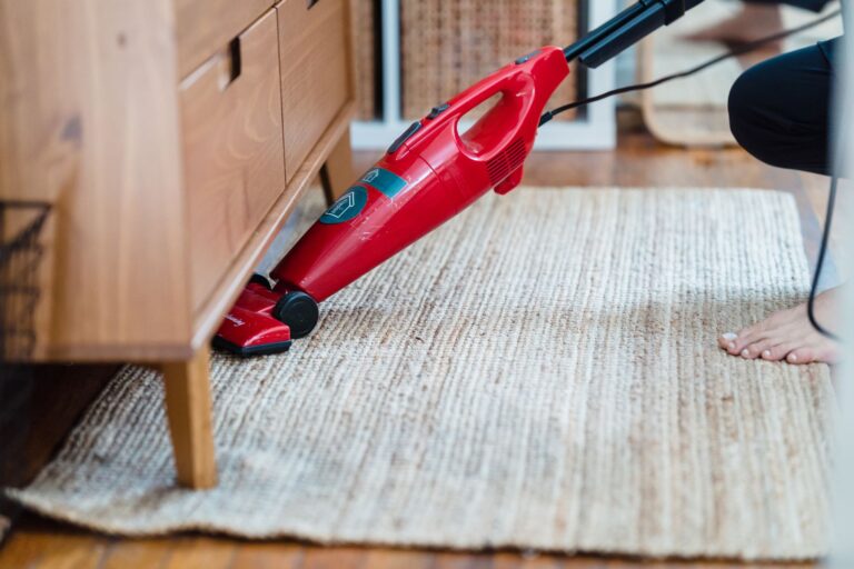 Best upright vacuum: vacuuming a jute rug with a red stick vacuum