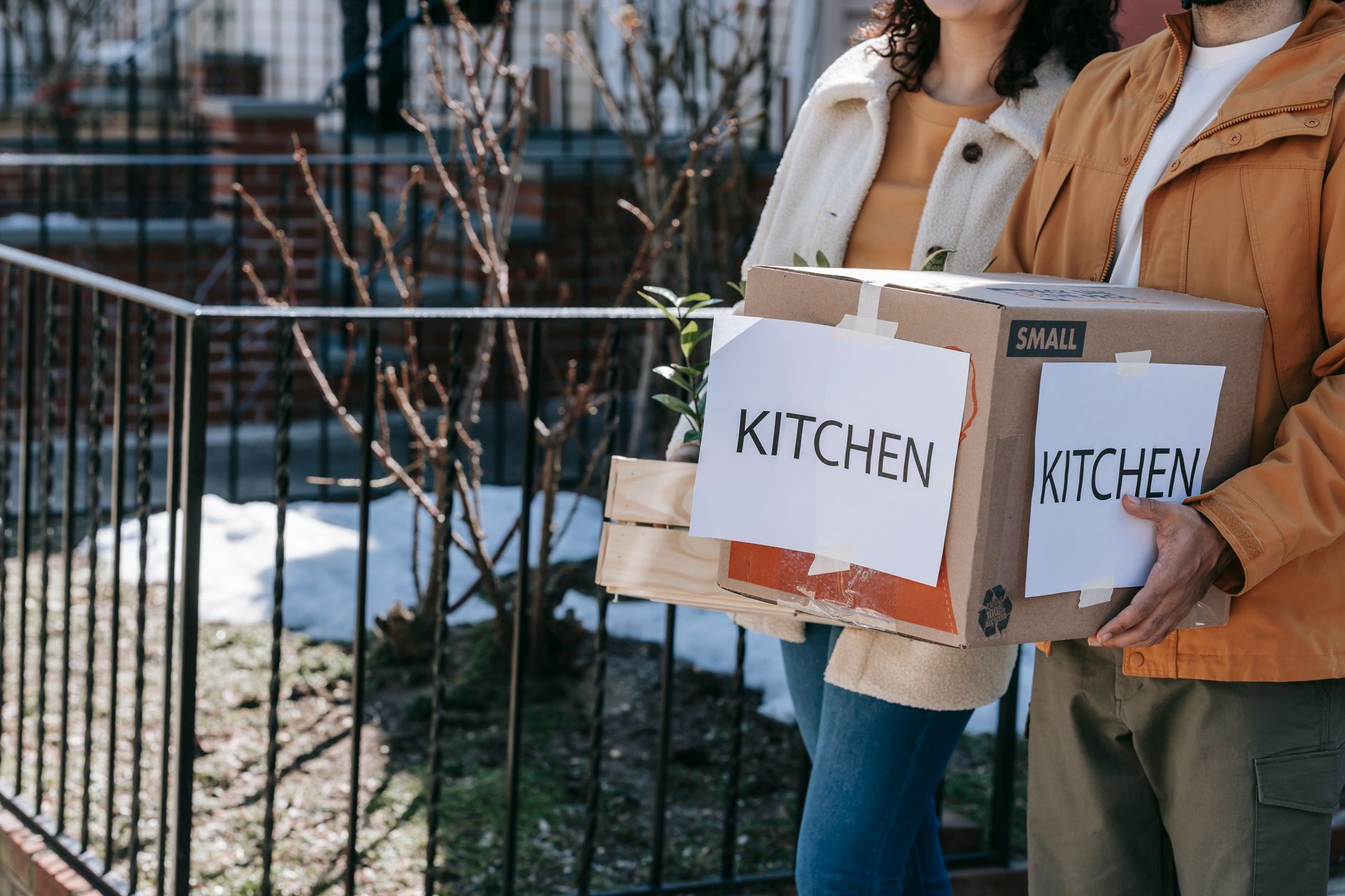Two people carrying a box labeled kitchen