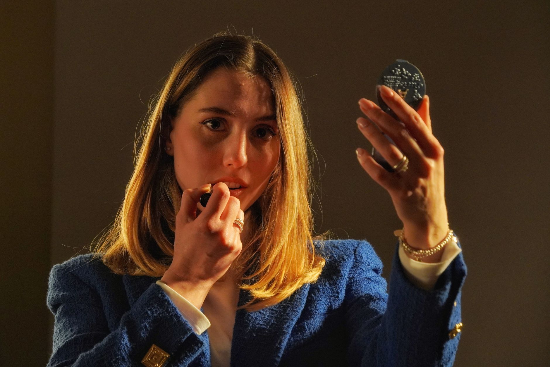 A woman applying makeup in front of a mirror