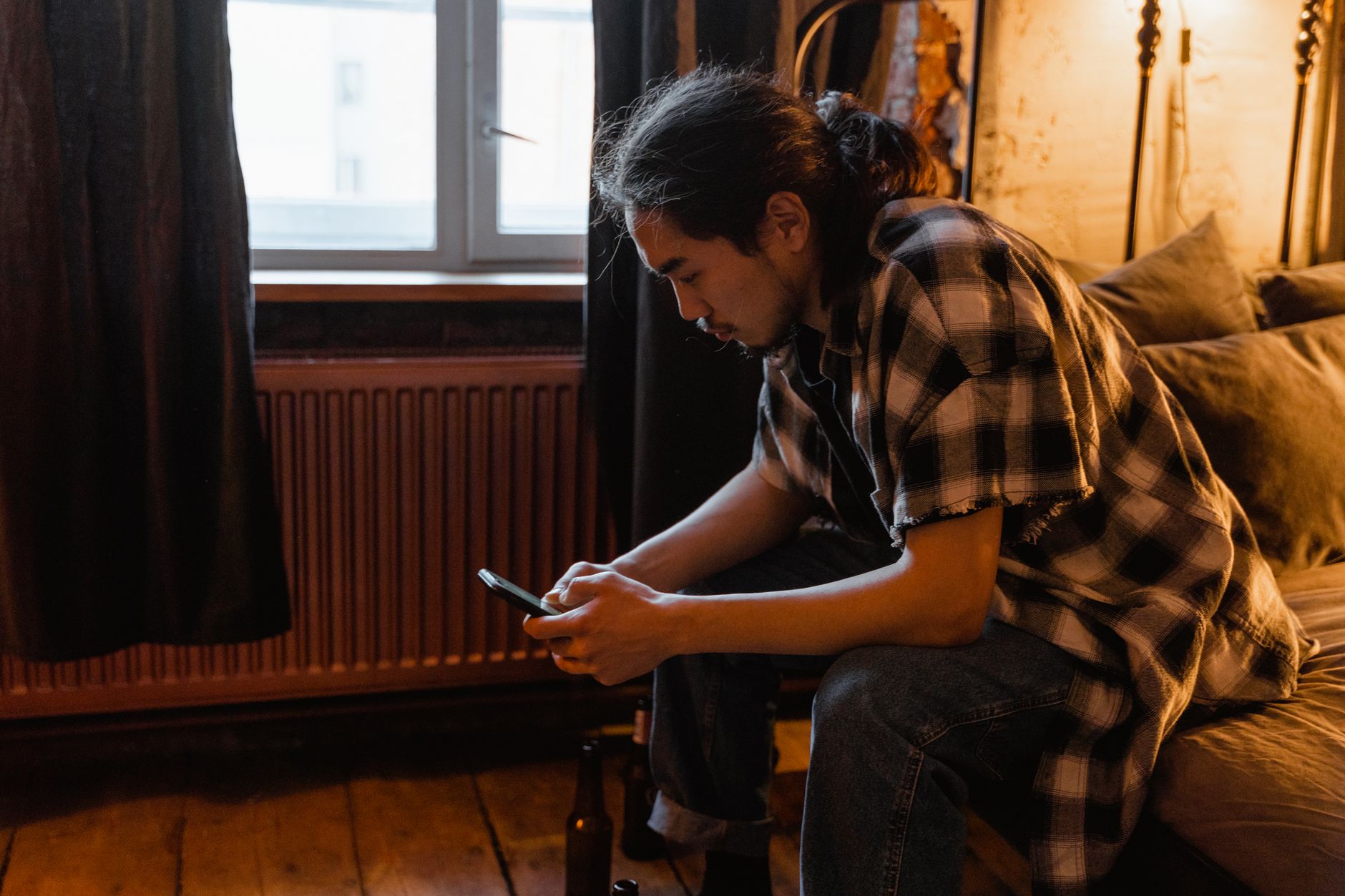 A man checking his phone on a sofa