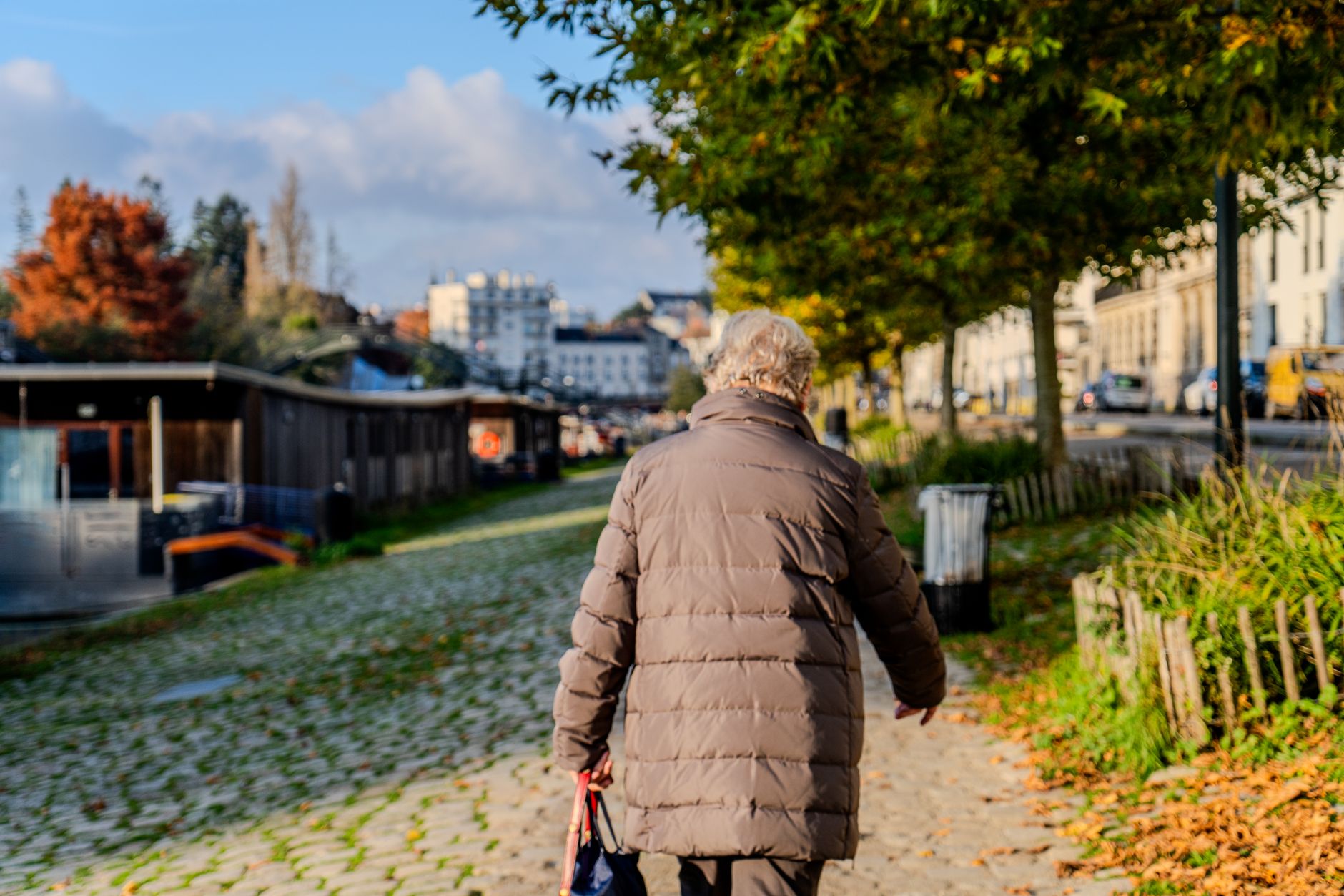 An older adult out for a walk on a sidewalk