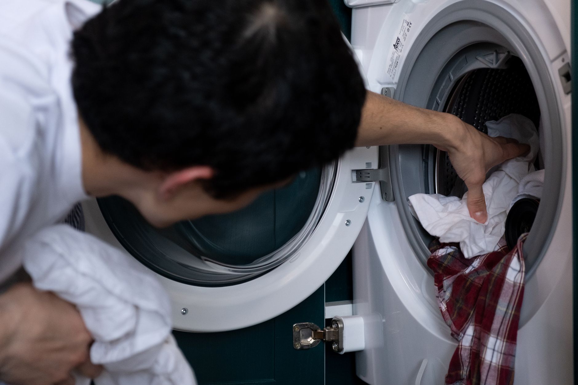 A man pulling laundry out of a front-loading washer