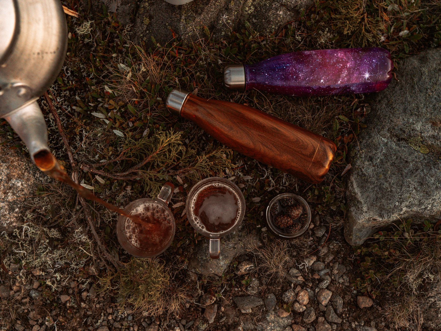 Insulated bottles and cups on rocky ground