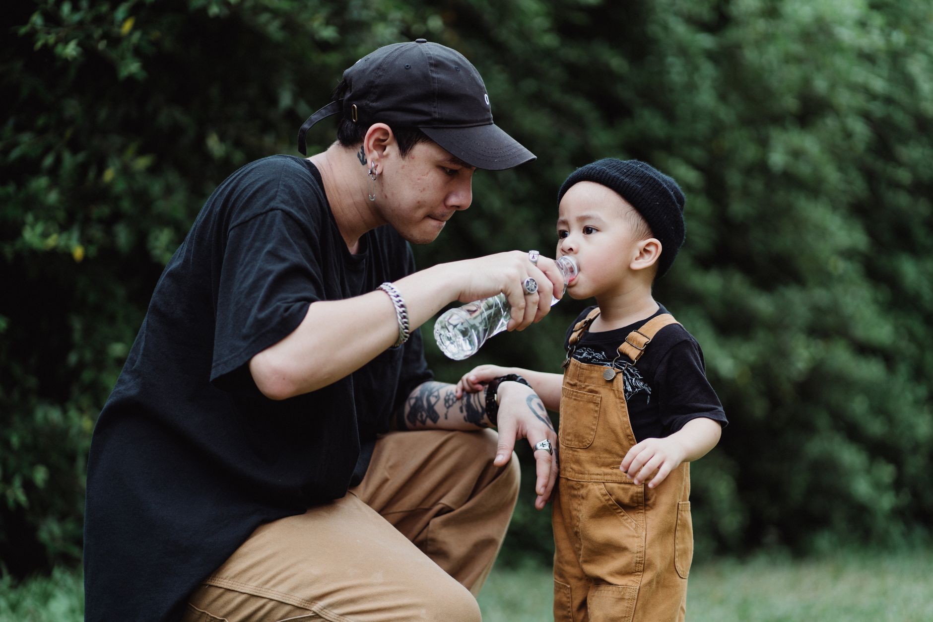 A man helping a toddler drink from a bottle