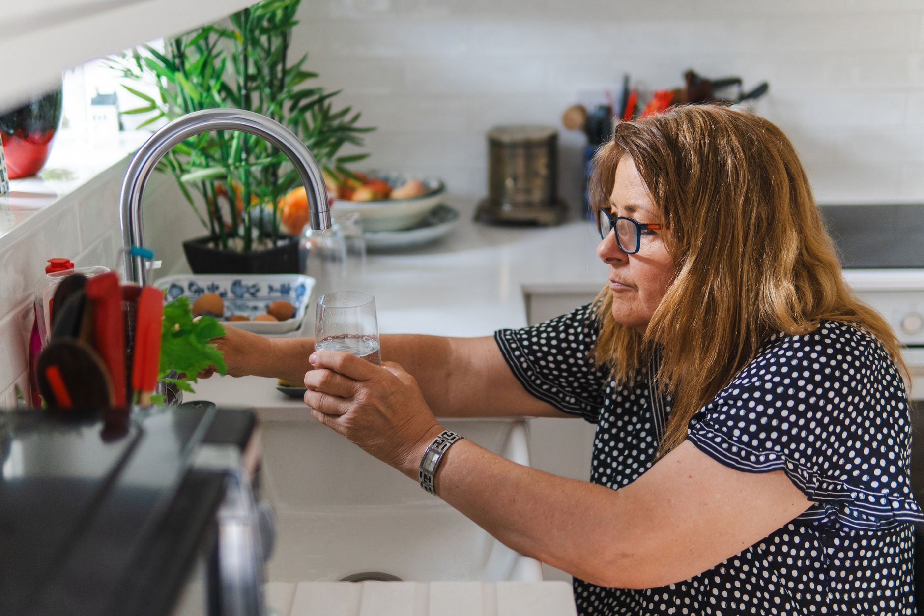 Best water filter: filling a glass of water at a kitchen faucet