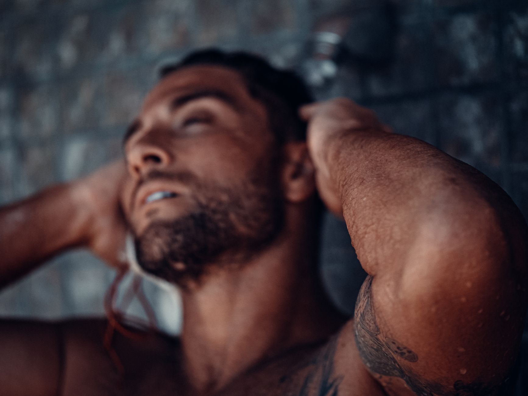 A man rinsing his hair in a shower