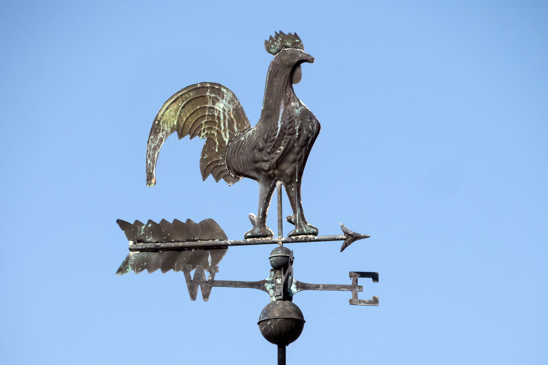A wind vane on a rooftop against the sky